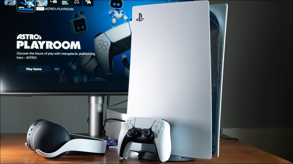 Eine Sony PlayStation 5 Konsole auf einem Schreibtisch mit einem Controller, Kopfhörern und einem Monitor.