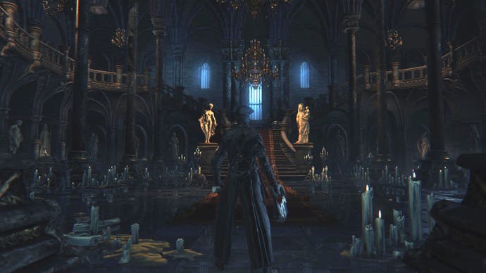 Ein Bloodborne-Spielercharakter steht in einem großen Raum in einem verschnörkelten gotischen Schloss. Der Raum ist übersät mit Kerzen, die nicht viel Licht spenden.